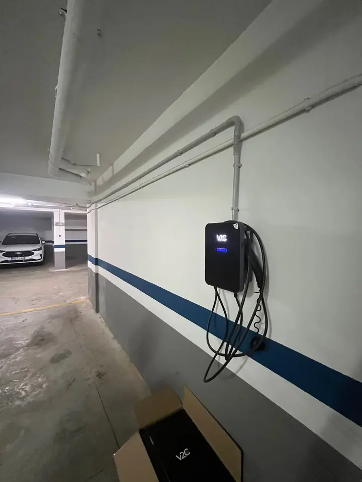 Cargador V2C Trydan en la pared de un garaje con canalización vista y cable recogido